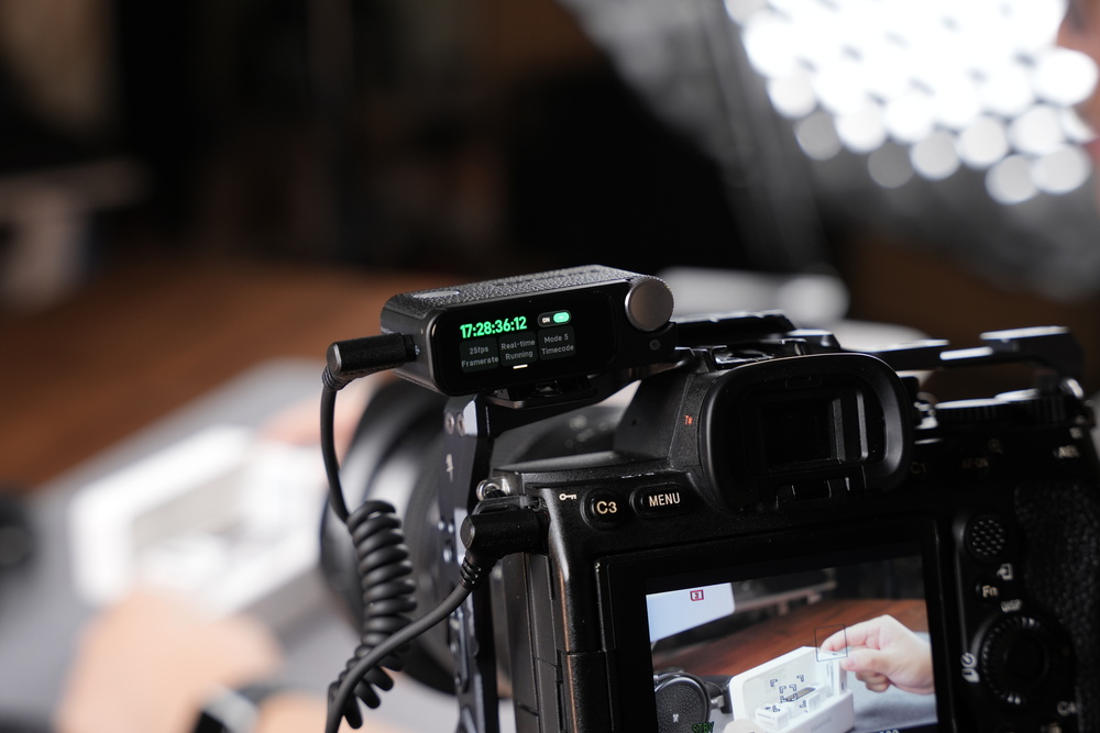 Camera rig with an external audio recorder displaying timecode, mounted on top.
