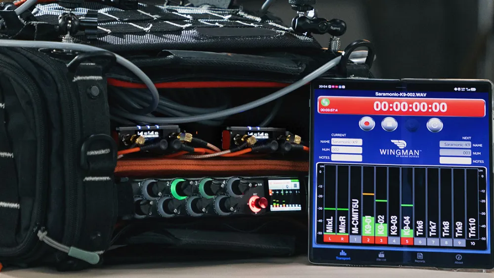 A tablet running the Wingman app monitors live audio from a Saramonic wireless microphone system connected to a Sound Devices mixer, displaying recording levels within a sound bag.